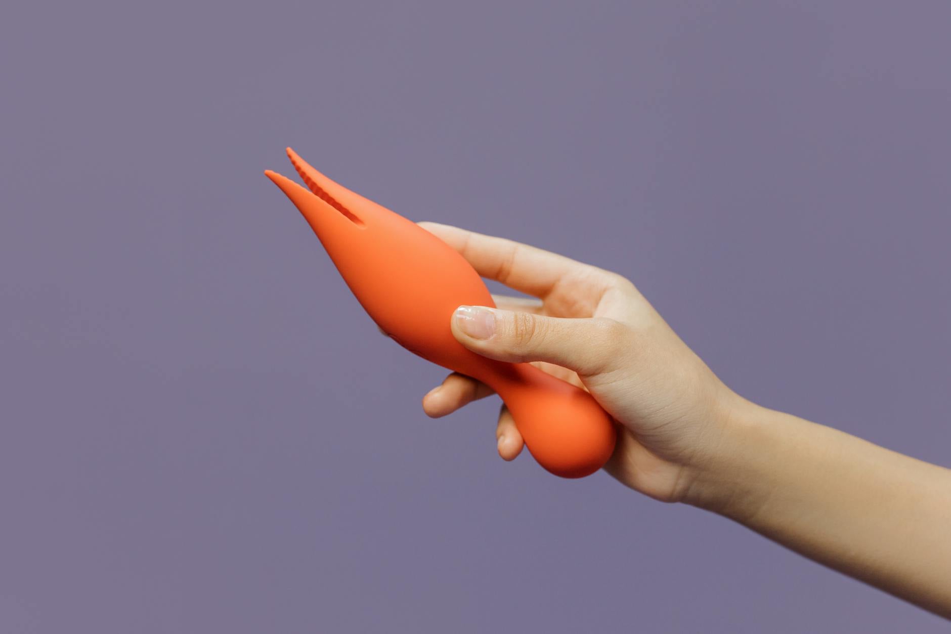 Gros plan d'un vibromasseur citron tenu à la main sur fond violet